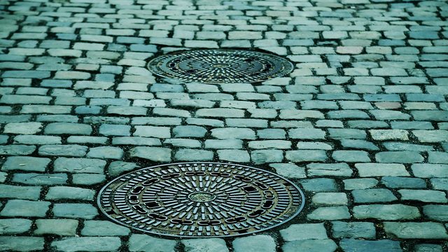 Kanaldeckel in einer gepflasterten Straße