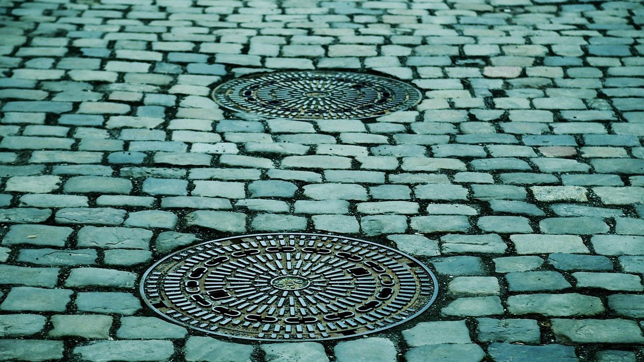 Kanaldeckel in einer gepflasterten Straße