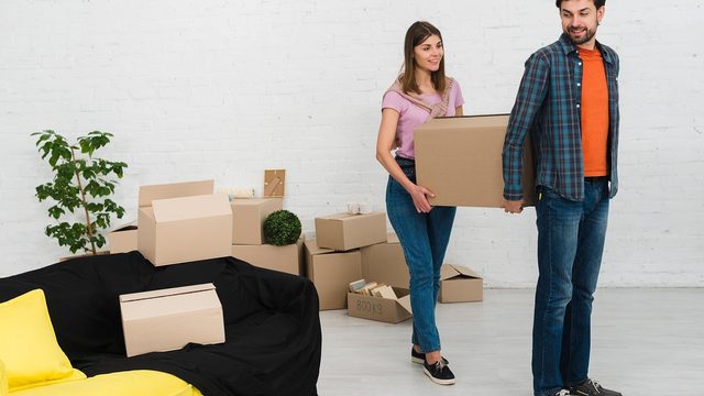 Paar mit Umzugskartons in einer leeren Wohnung